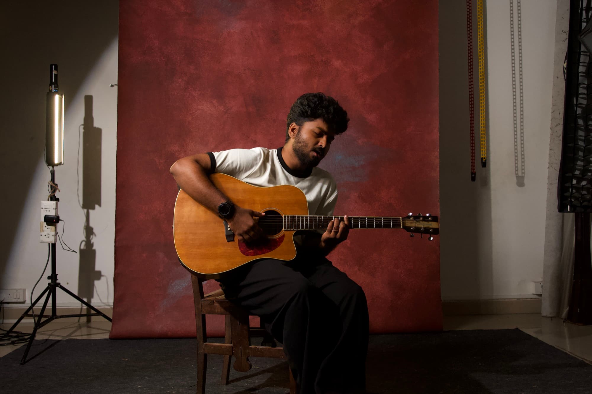 Ajay Nathan playing acoustic guitar in the studio